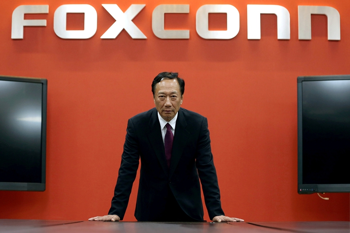 Who founded Foxconn, which produces Apple's iPhone models, and when?